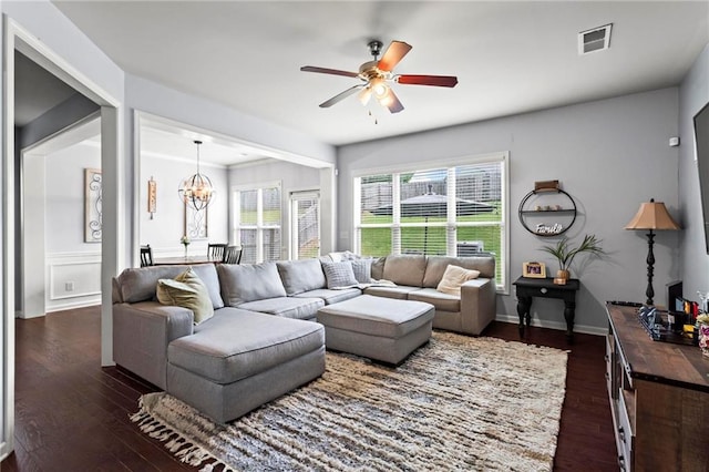 living area with dark wood-type flooring, visible vents, and ceiling fan with notable chandelier
