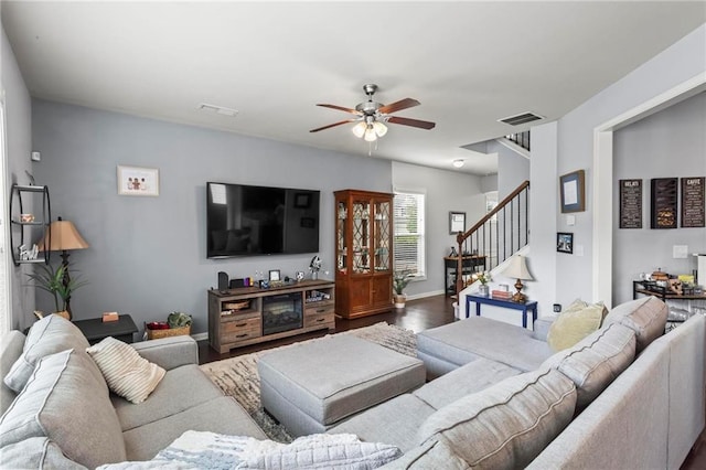 living room featuring wood finished floors, visible vents, stairs, and ceiling fan