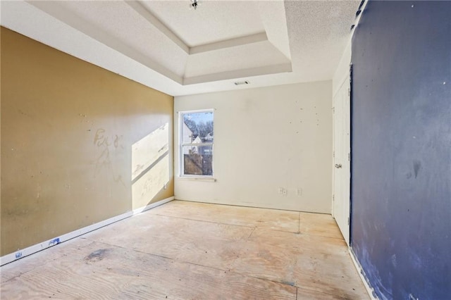 unfurnished room featuring a textured ceiling and a tray ceiling