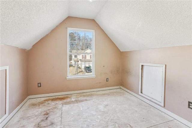 additional living space featuring vaulted ceiling and a textured ceiling