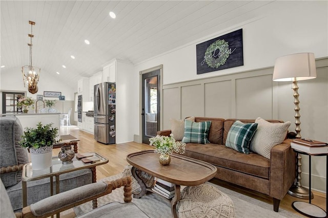 living room featuring a notable chandelier, light hardwood / wood-style flooring, vaulted ceiling, and wood ceiling