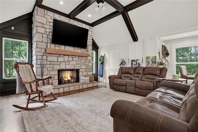 living room featuring a stone fireplace, light hardwood / wood-style flooring, and lofted ceiling with beams