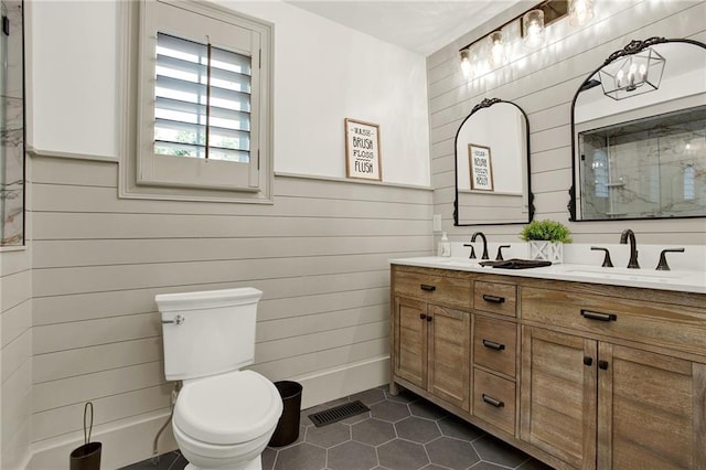 bathroom with wooden walls, tile patterned floors, vanity, and toilet