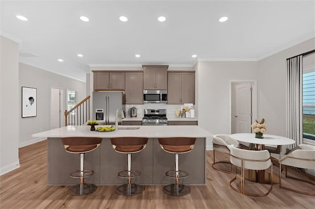 475 Azalea Xing, Dallas, GA 30132 - kitchen with baseboards, appliances with stainless steel finishes, a kitchen island with sink, backsplash, and light wood-style flooring
