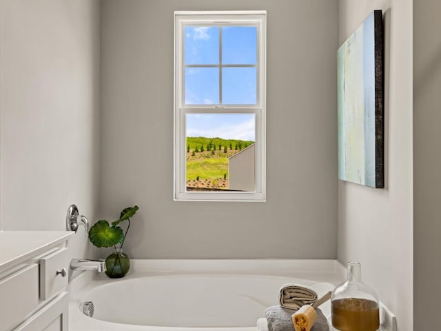 full bathroom featuring a healthy amount of sunlight, a garden tub, and vanity