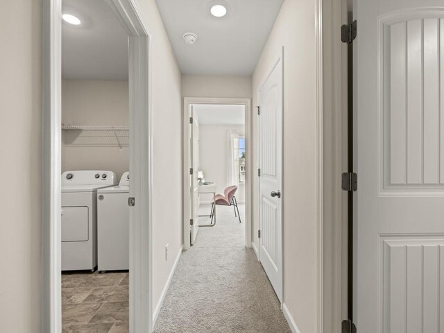 hall with light carpet, washer and clothes dryer, and baseboards