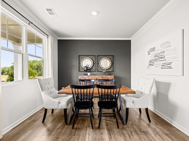 dining room with baseboards, visible vents, wood finished floors, and ornamental molding