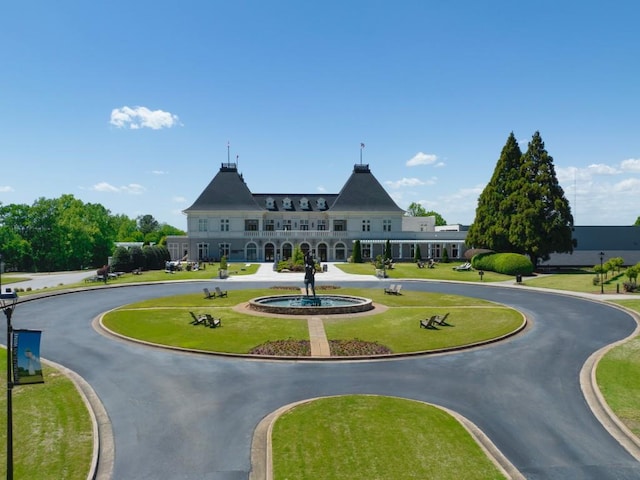 view of community with curved driveway and a lawn