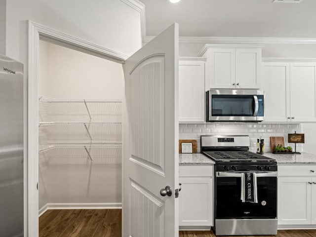 kitchen with light stone counters, dark wood-style flooring, stainless steel appliances, backsplash, and white cabinetry