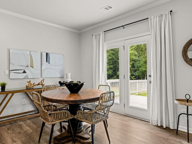 dining space with ornamental molding, plenty of natural light, wood finished floors, and visible vents