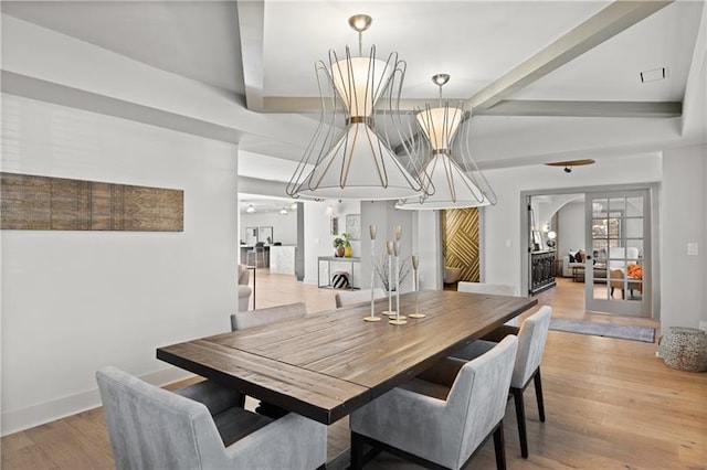 dining area with arched walkways, baseboards, light wood-style flooring, and beam ceiling