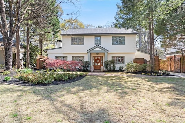 view of front of property with stucco siding, a front yard, and fence