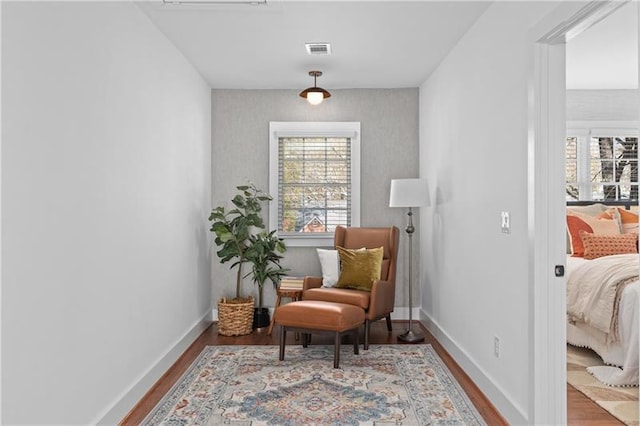 sitting room featuring a healthy amount of sunlight, baseboards, wood finished floors, and visible vents
