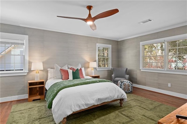 bedroom featuring baseboards, multiple windows, wood finished floors, and visible vents