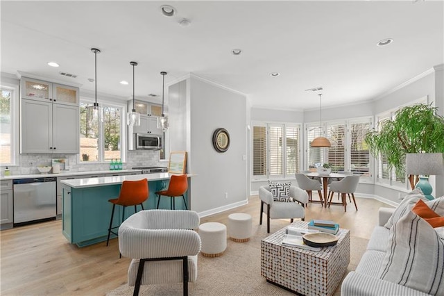living area featuring crown molding, recessed lighting, baseboards, light wood-type flooring, and visible vents
