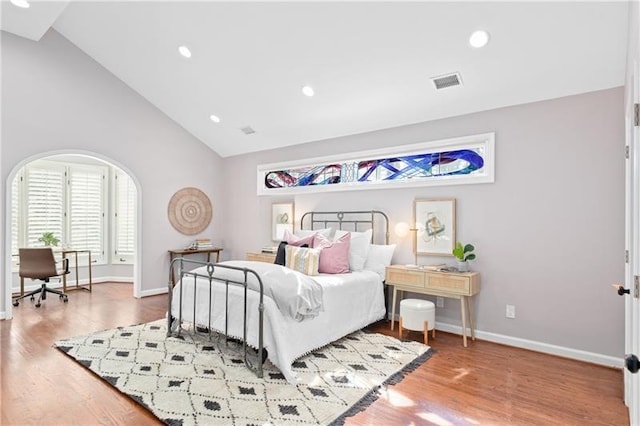bedroom with visible vents, baseboards, wood finished floors, and high vaulted ceiling
