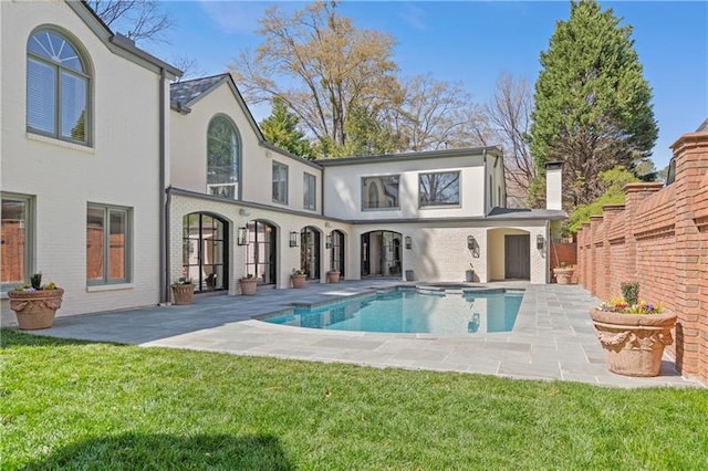 back of property with a patio, an outdoor pool, stucco siding, and a yard