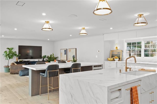 kitchen with decorative light fixtures, a spacious island, a sink, white cabinets, and open floor plan