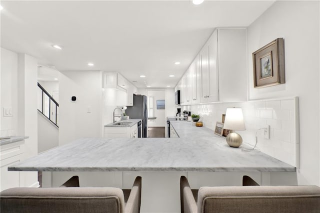 12 Ivy Rdg NE, Atlanta, GA 30342 - kitchen featuring appliances with stainless steel finishes, white cabinetry, a breakfast bar area, and recessed lighting