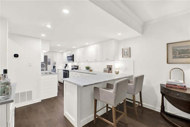 12 Ivy Rdg NE, Atlanta, GA 30342 - kitchen featuring appliances with stainless steel finishes, white cabinetry, a peninsula, a kitchen breakfast bar, and dark wood-style flooring
