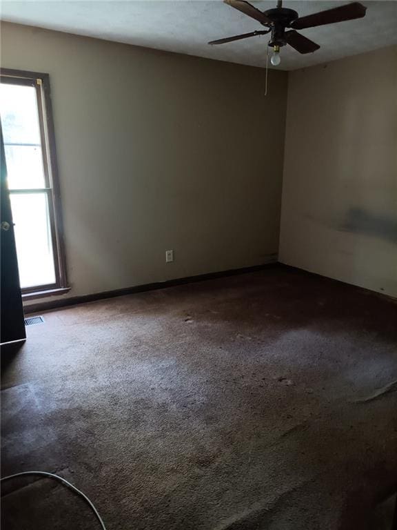 carpeted spare room featuring ceiling fan and plenty of natural light