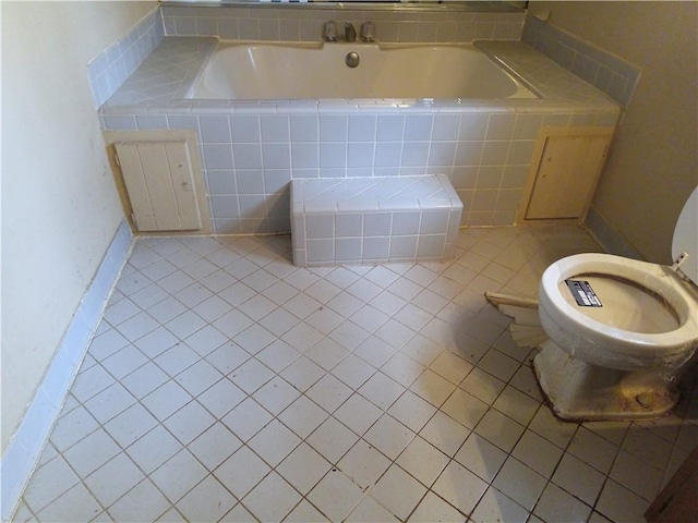 bathroom featuring tile patterned flooring, toilet, and tiled tub