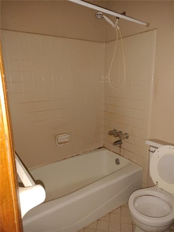 bathroom with tile patterned floors, tiled shower / bath combo, and toilet