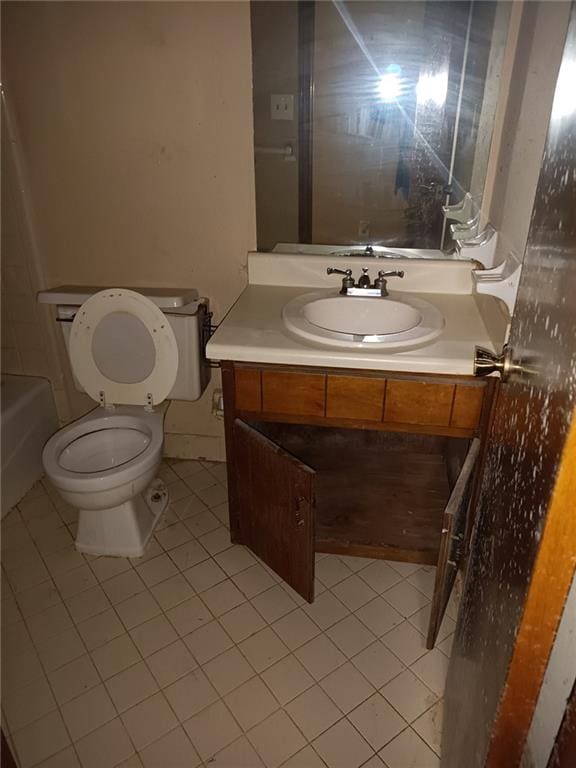 bathroom featuring toilet, vanity, tile patterned floors, and a washtub