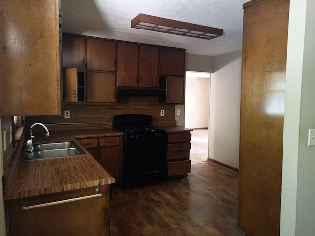 kitchen with backsplash, sink, dark hardwood / wood-style floors, and black gas range oven