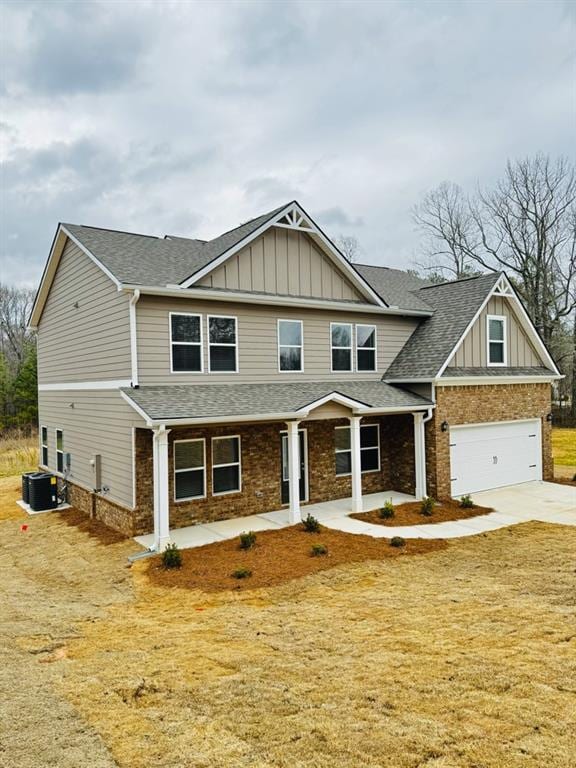 craftsman-style house with a shingled roof, board and batten siding, concrete driveway, and brick siding