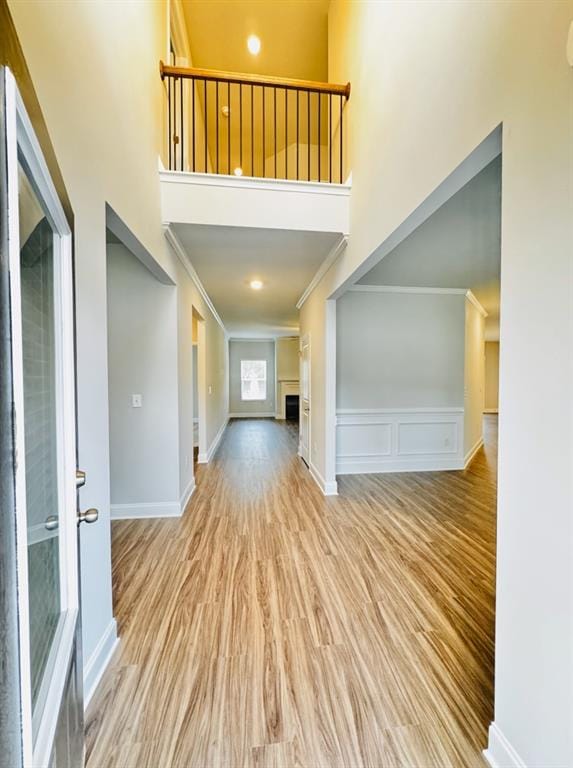foyer with ornamental molding, wood finished floors, and a towering ceiling