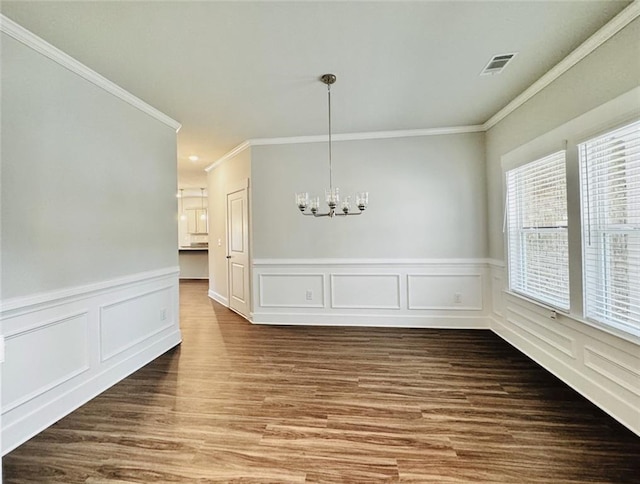 unfurnished dining area with visible vents, crown molding, wainscoting, wood finished floors, and a chandelier