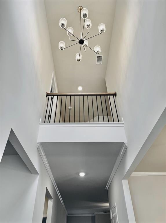 stairs with crown molding, visible vents, a chandelier, and a towering ceiling