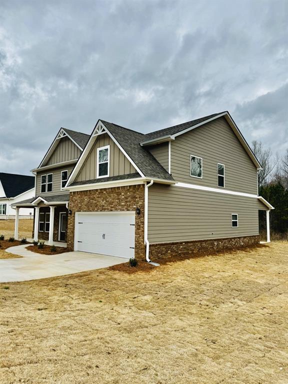 view of front of home featuring a shingled roof, an attached garage, brick siding, board and batten siding, and concrete driveway