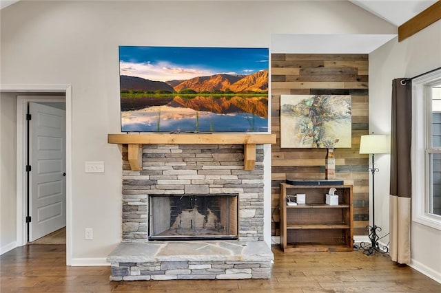 unfurnished living room with vaulted ceiling, hardwood / wood-style flooring, and a stone fireplace