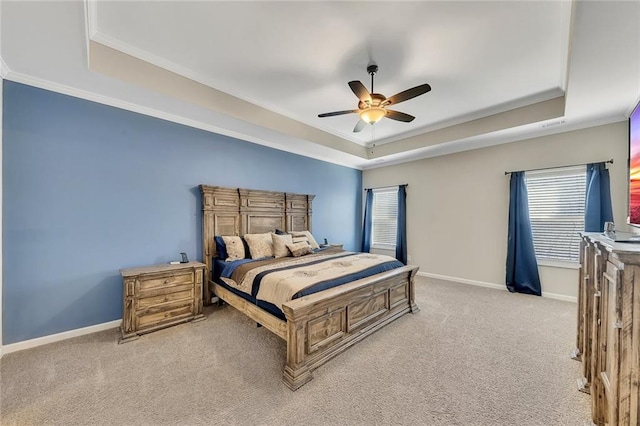 carpeted bedroom with a tray ceiling, ceiling fan, and ornamental molding