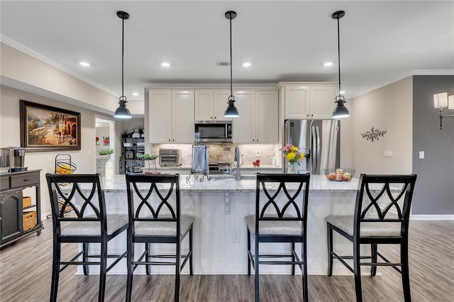 kitchen featuring white cabinets, appliances with stainless steel finishes, light stone counters, and pendant lighting