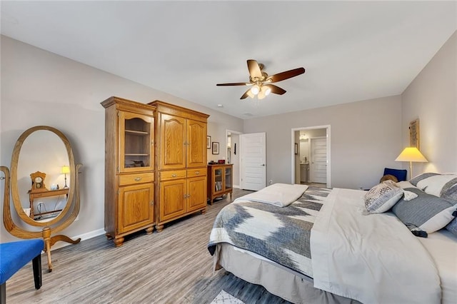 bedroom featuring ceiling fan, light wood-type flooring, and ensuite bath