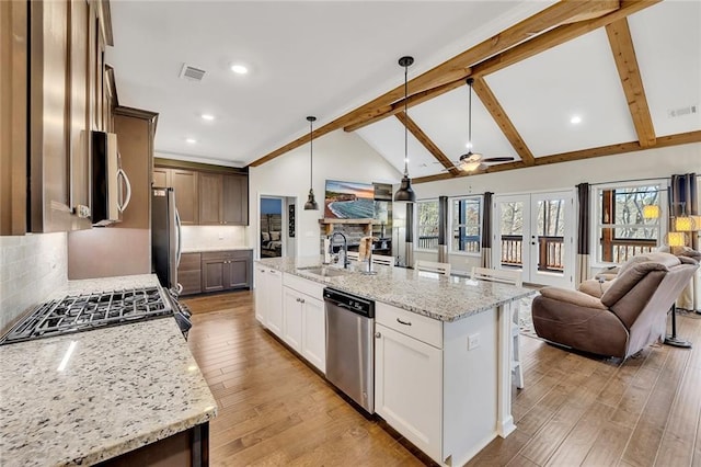 kitchen with stainless steel appliances, ceiling fan, pendant lighting, beamed ceiling, and white cabinets