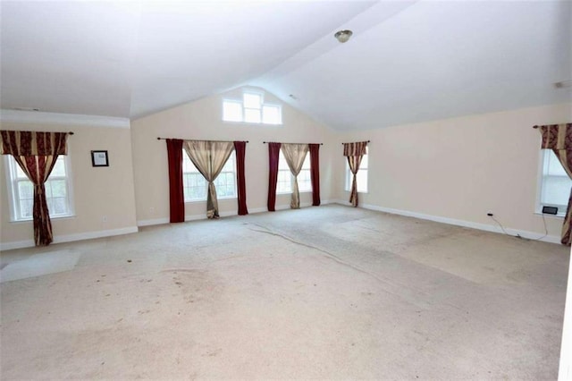 spare room with light carpet, lofted ceiling, and baseboards