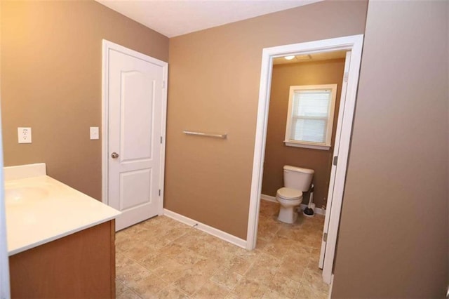 bathroom featuring vanity, toilet, and baseboards