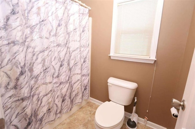 bathroom featuring toilet, a shower with curtain, baseboards, and tile patterned floors