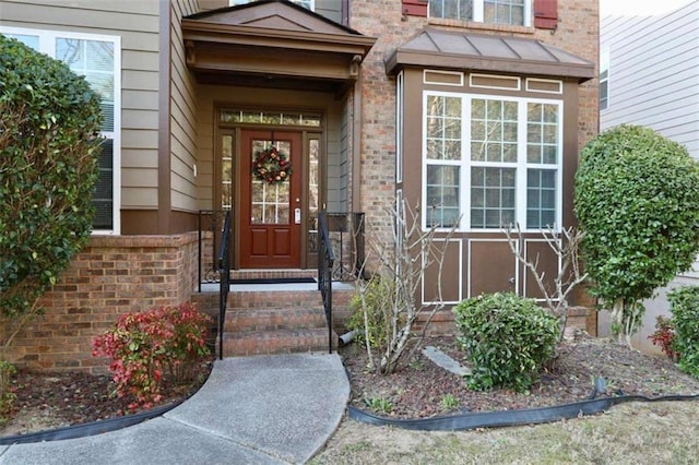 entrance to property with brick siding and a standing seam roof