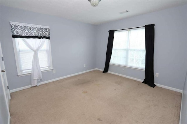 unfurnished room featuring light colored carpet, visible vents, and baseboards