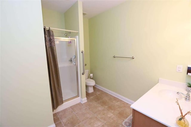 bathroom featuring toilet, a shower stall, vanity, tile patterned flooring, and baseboards