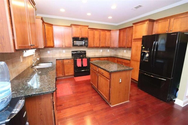 kitchen featuring dark wood-type flooring, visible vents, a sink, and black appliances