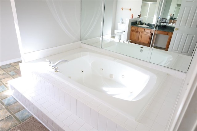 bathroom featuring vanity, a relaxing tiled tub, and toilet