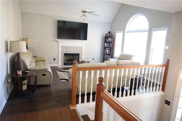 living room with a tile fireplace, ceiling fan, dark hardwood / wood-style flooring, and vaulted ceiling