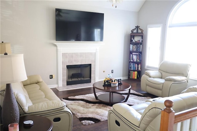 living room with a tile fireplace, dark hardwood / wood-style floors, and vaulted ceiling