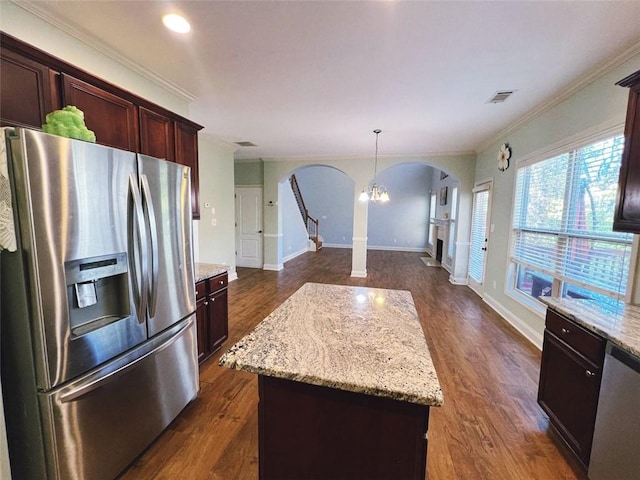 kitchen featuring hanging light fixtures, ornamental molding, appliances with stainless steel finishes, a kitchen island, and dark hardwood / wood-style flooring